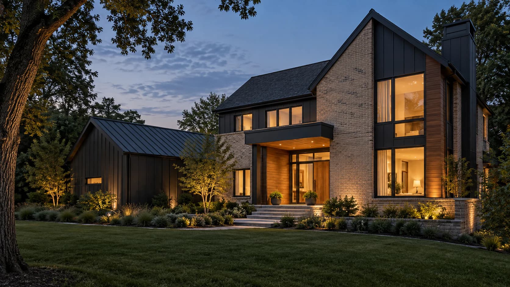 Two-story brick, timber, and dark metal home at blue hour, its tall windows lit from within above a landscaped lawn.